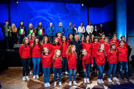 Immagine:
Cfr.: Missioni Don Bosco e 'Gravissimus Educationis' - Progetto educativo globale
=  Dicembre 2021: Christmas Contest con il compositore Mogol e la Nazionale Cantanti =
Nell'immagine-foto:
Cantanti, musicisti, sportivi (Fiona May terza da destra in alto) e il coro gLe dolci noteh.
[Ufficio Stampa Missioni Don Bosco - missionidonbosco.org]